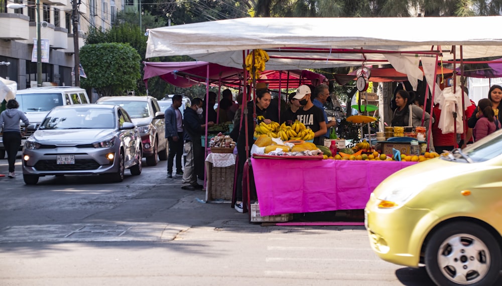 a yellow car is parked in front of a fruit stand