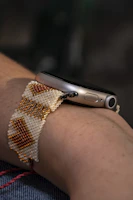 Close-up of hands crafting a DIY fitness tracker holder with natural wood and bright paint.