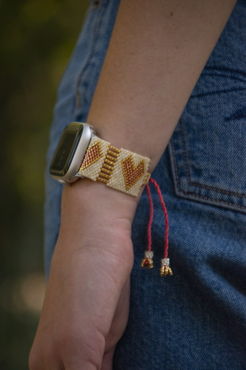 a person wearing an apple watch with a beaded bracelet