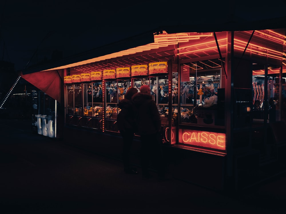 a couple of people standing outside of a food stand