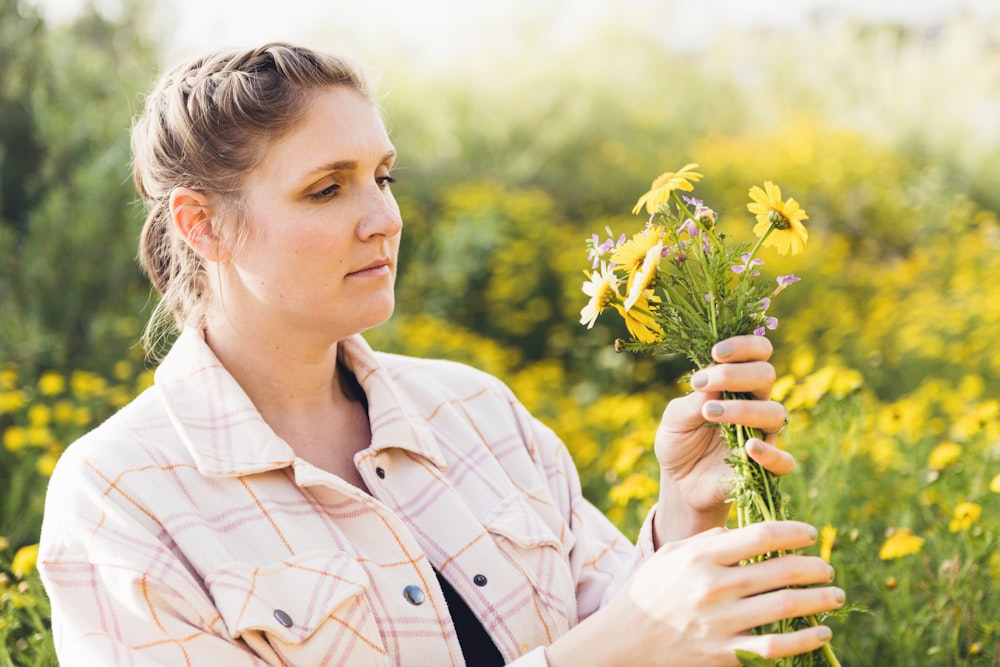 a woman holding a bunch of flowers in a field