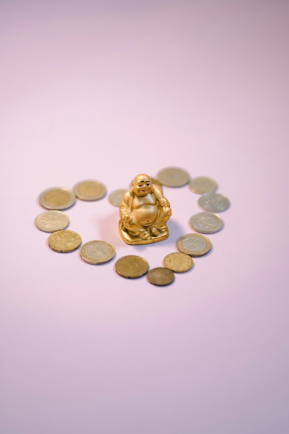 a buddha statue surrounded by coins on a purple background