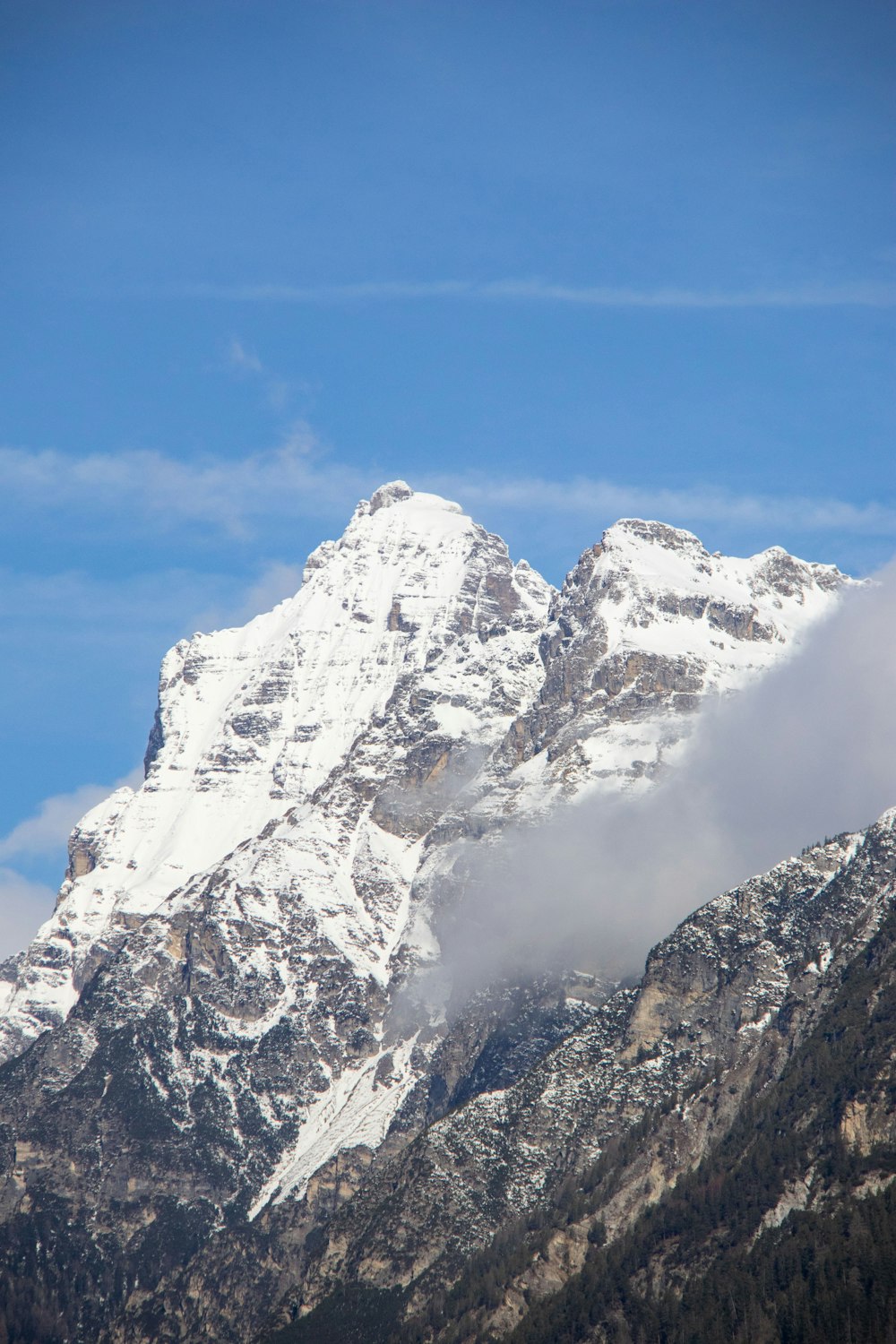 a snow covered mountain with a cloud in the foreground