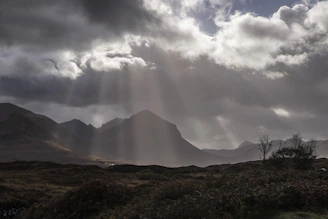 the sun is shining through the clouds over the mountains