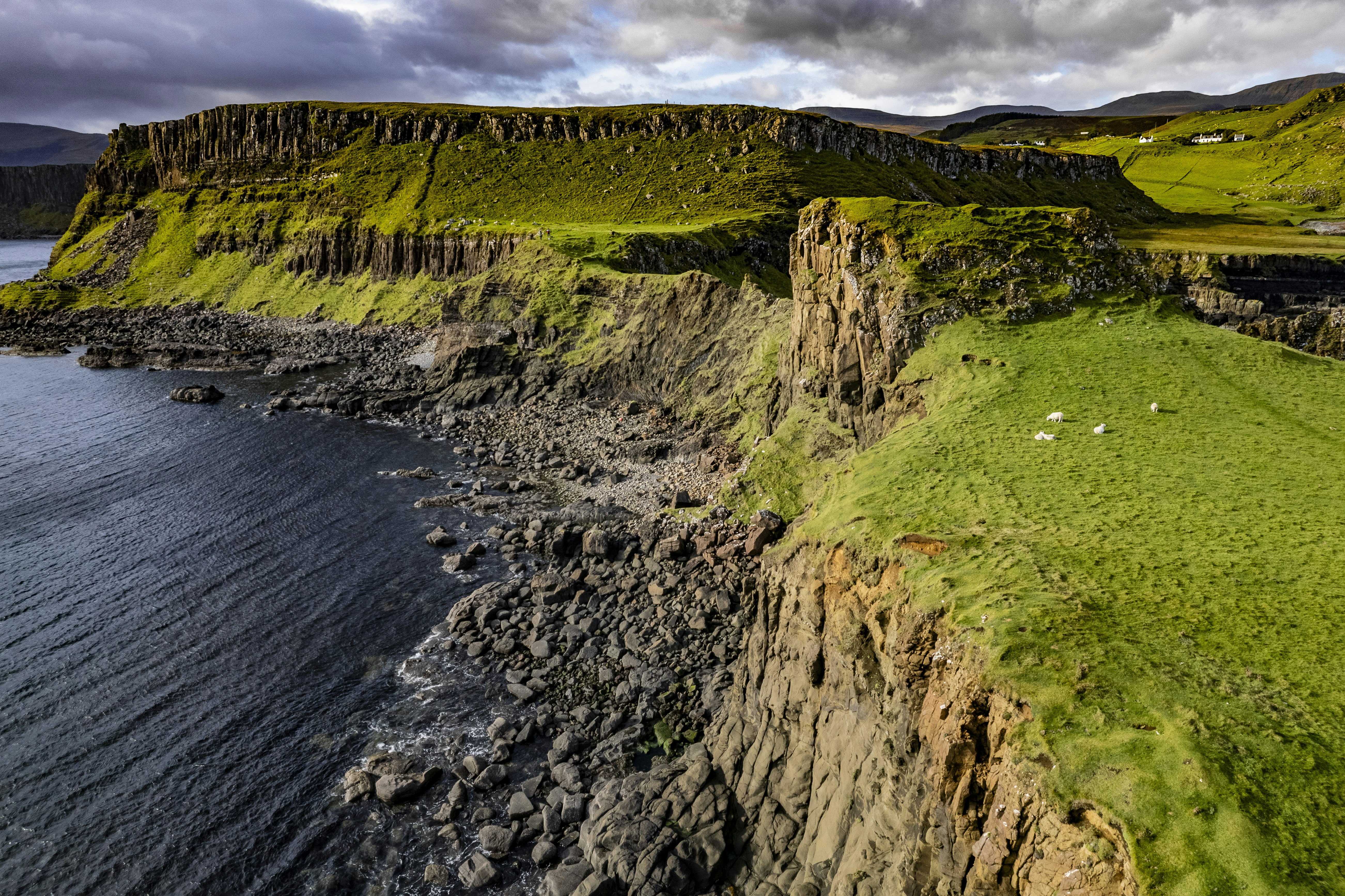 a grassy cliff with a body of water in the foreground