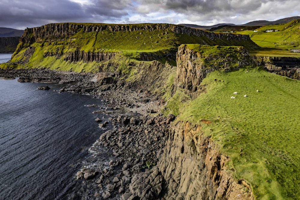 a grassy cliff with a body of water in the foreground