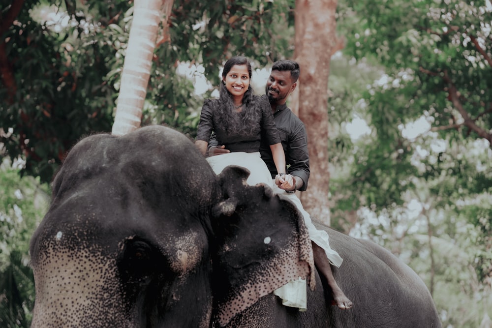 a man and woman riding on the back of an elephant