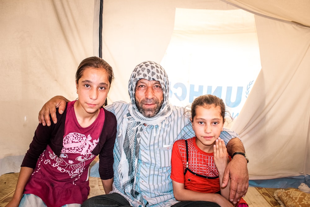 a man and two children sitting in a tent