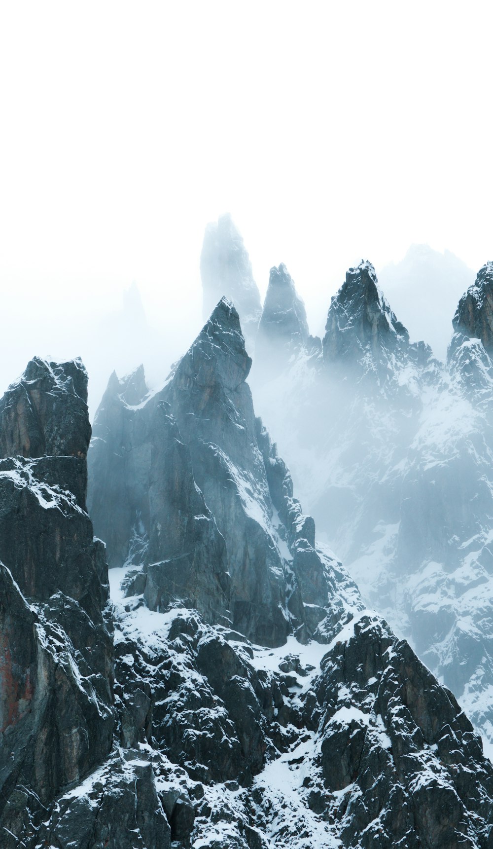 a group of mountains covered in snow and fog