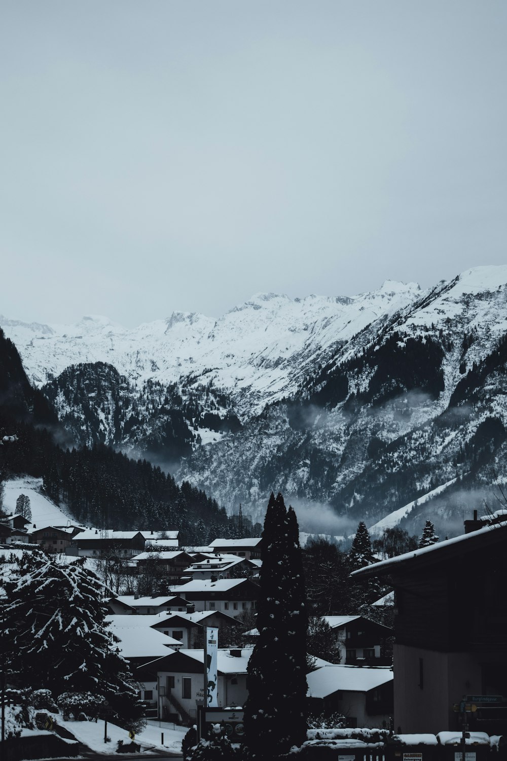 a snow covered mountain range with houses in the foreground