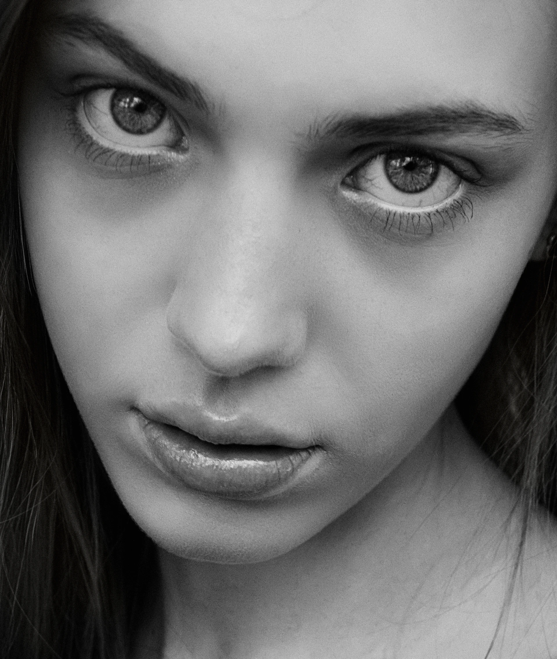 A close-up portrait of a person with intense eyes, shot in monochrome to emphasize emotion and depth.