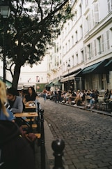 a group of people sitting at tables on a sidewalk