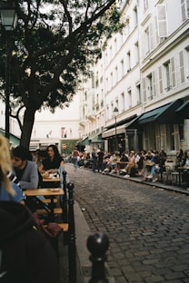 a group of people sitting at tables on a sidewalk
