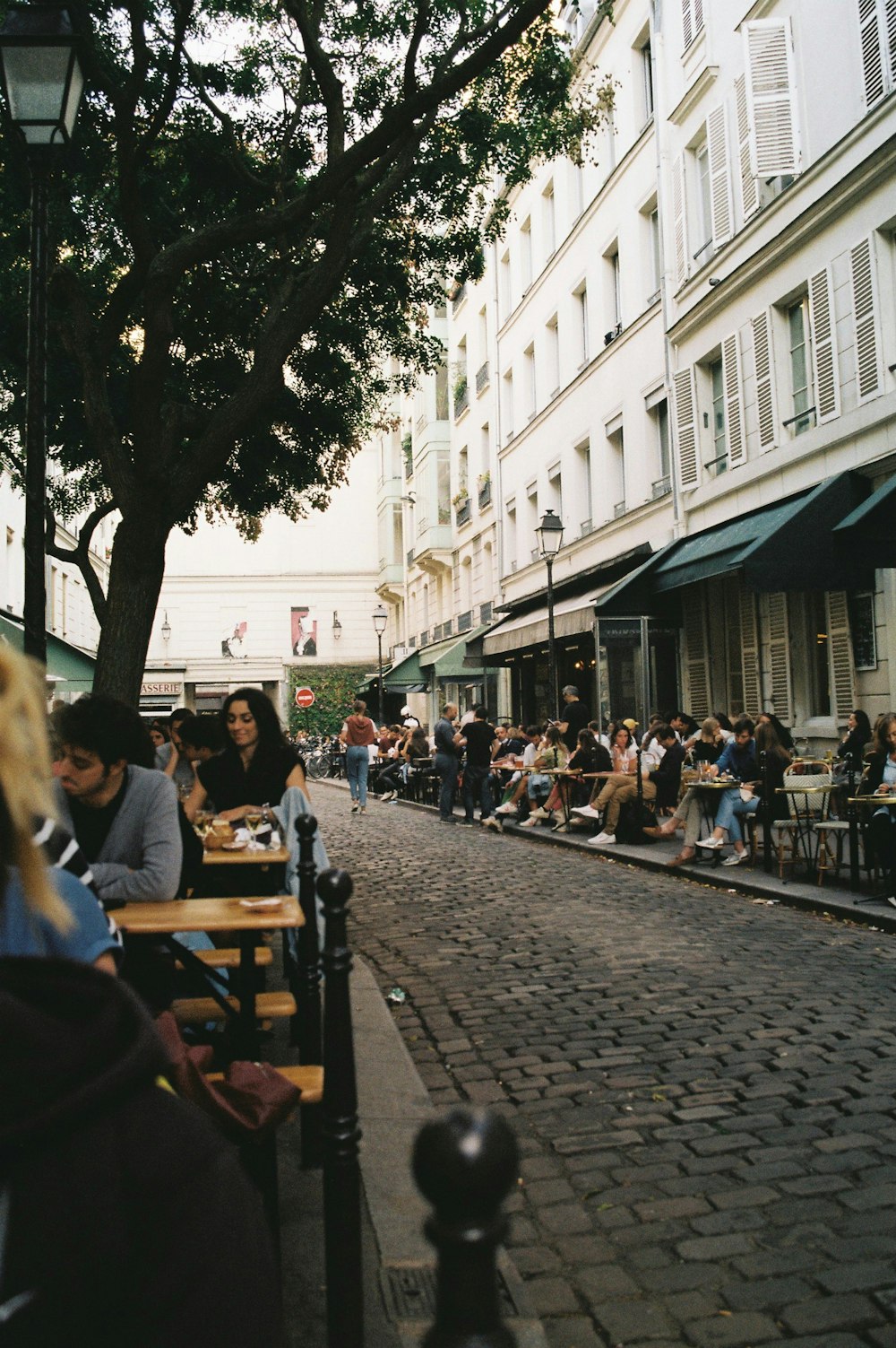 a group of people sitting at tables on a sidewalk