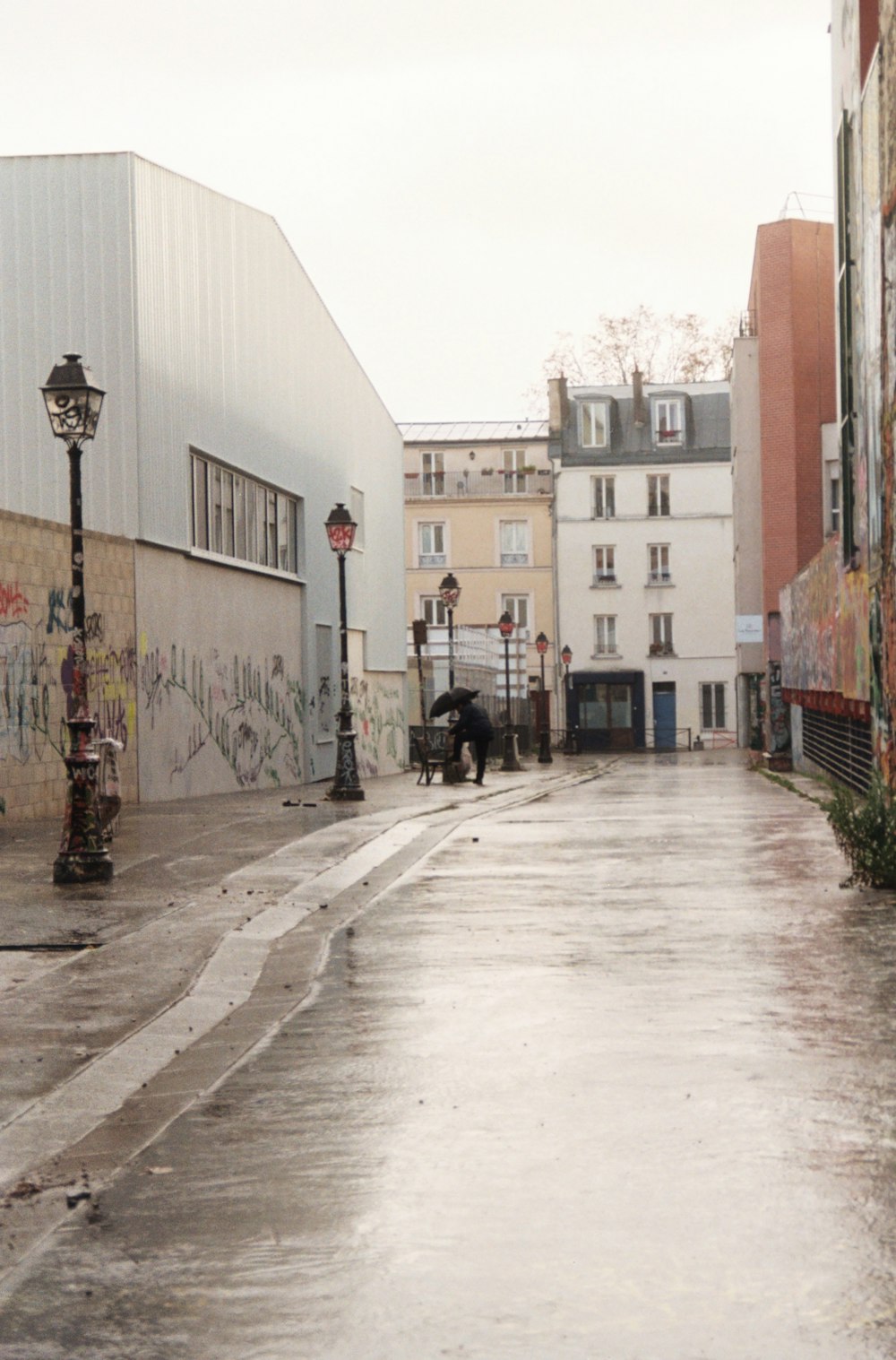 a wet street with buildings and a street light