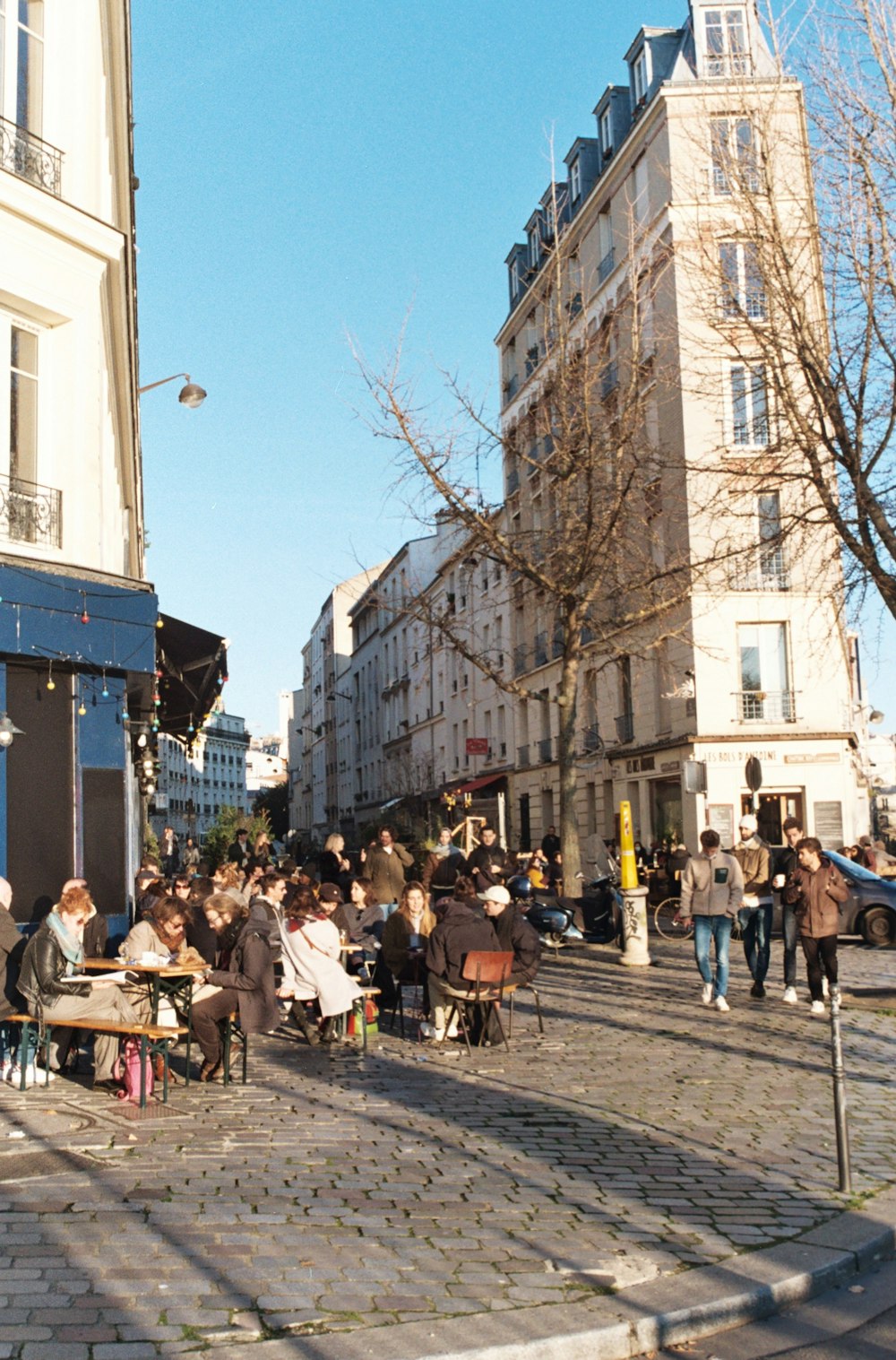 a group of people sitting at a table on a cobblestone street