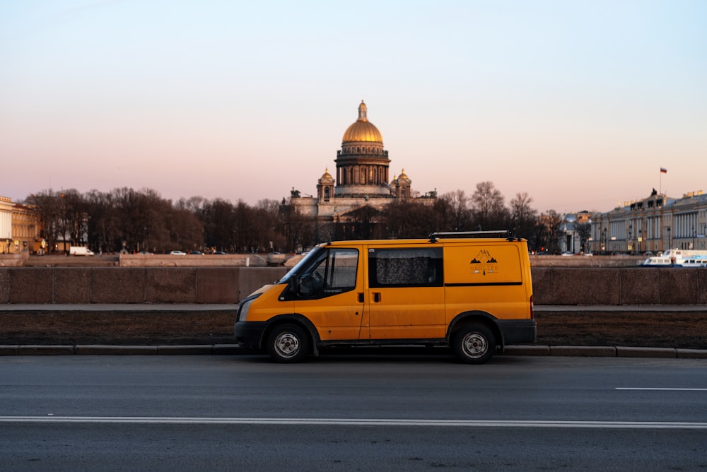 a yellow van driving down a street next to a building