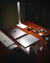 a wooden desk topped with a laptop computer next to a keyboard