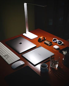 a wooden desk topped with a laptop computer next to a keyboard