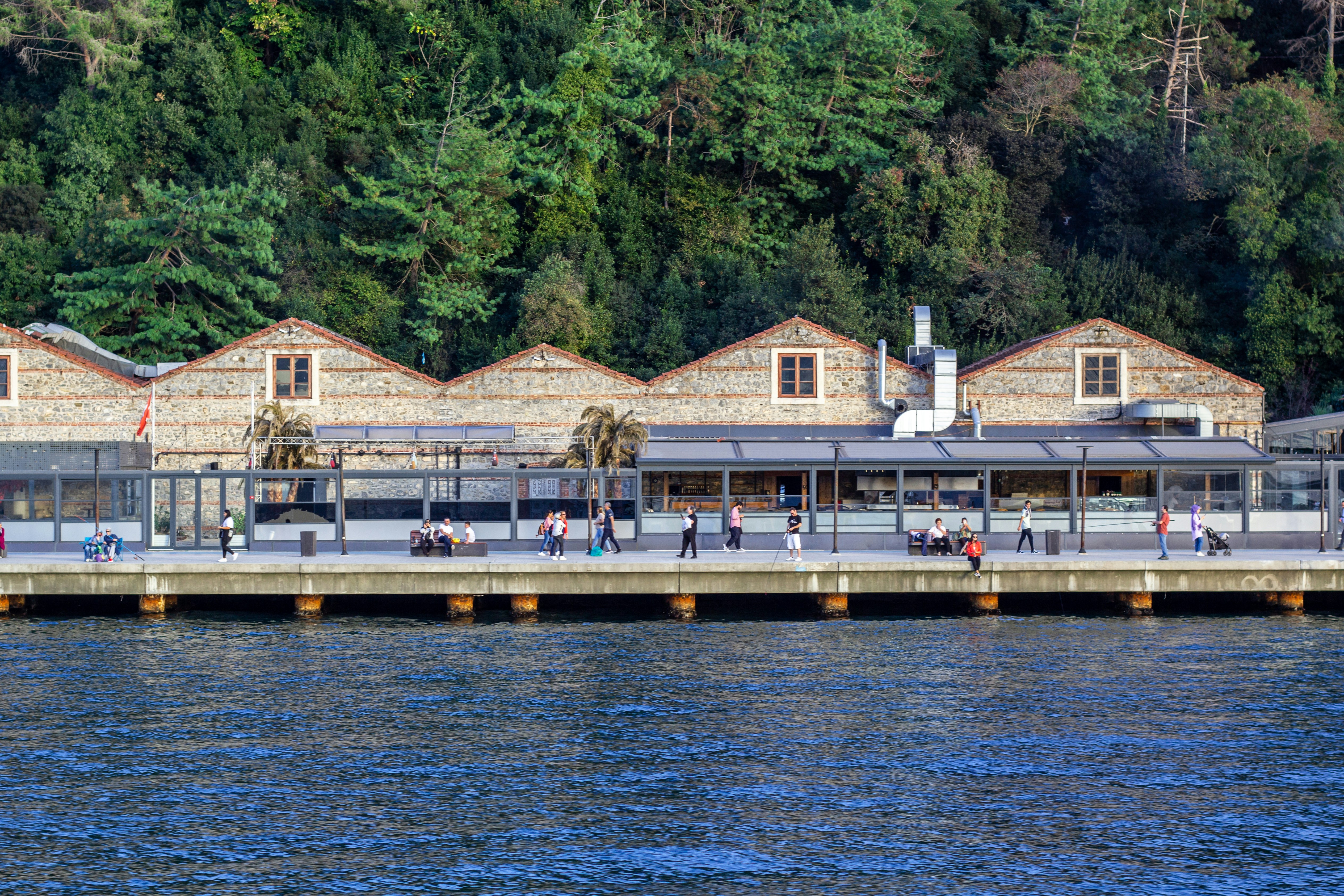 a group of people standing on a pier next to a body of water