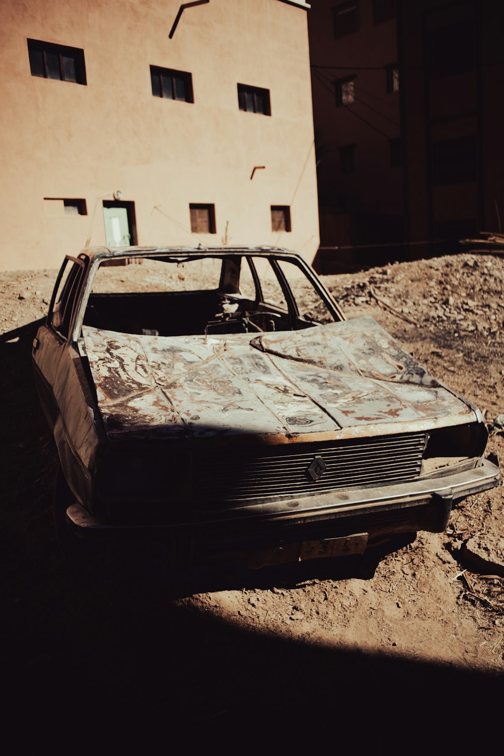 a rusted out car sitting in front of a building