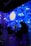 A digital art installation features projections of Van Gogh's Starry Night, casting vibrant swirls of blue, yellow, and white across the walls. People are seated and standing in the room, some silhouetted against the illuminated backdrop, creating an immersive experience.