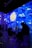 A digital art installation features projections of Van Gogh's Starry Night, casting vibrant swirls of blue, yellow, and white across the walls. People are seated and standing in the room, some silhouetted against the illuminated backdrop, creating an immersive experience.