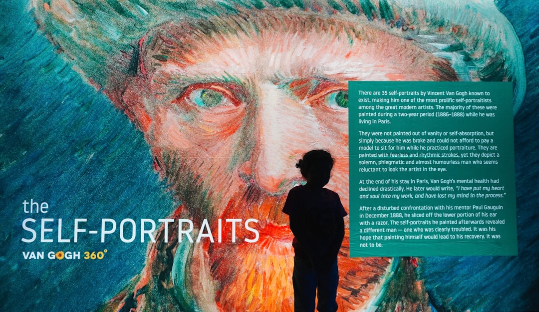 a man standing in front of a painting of a man with a beard,