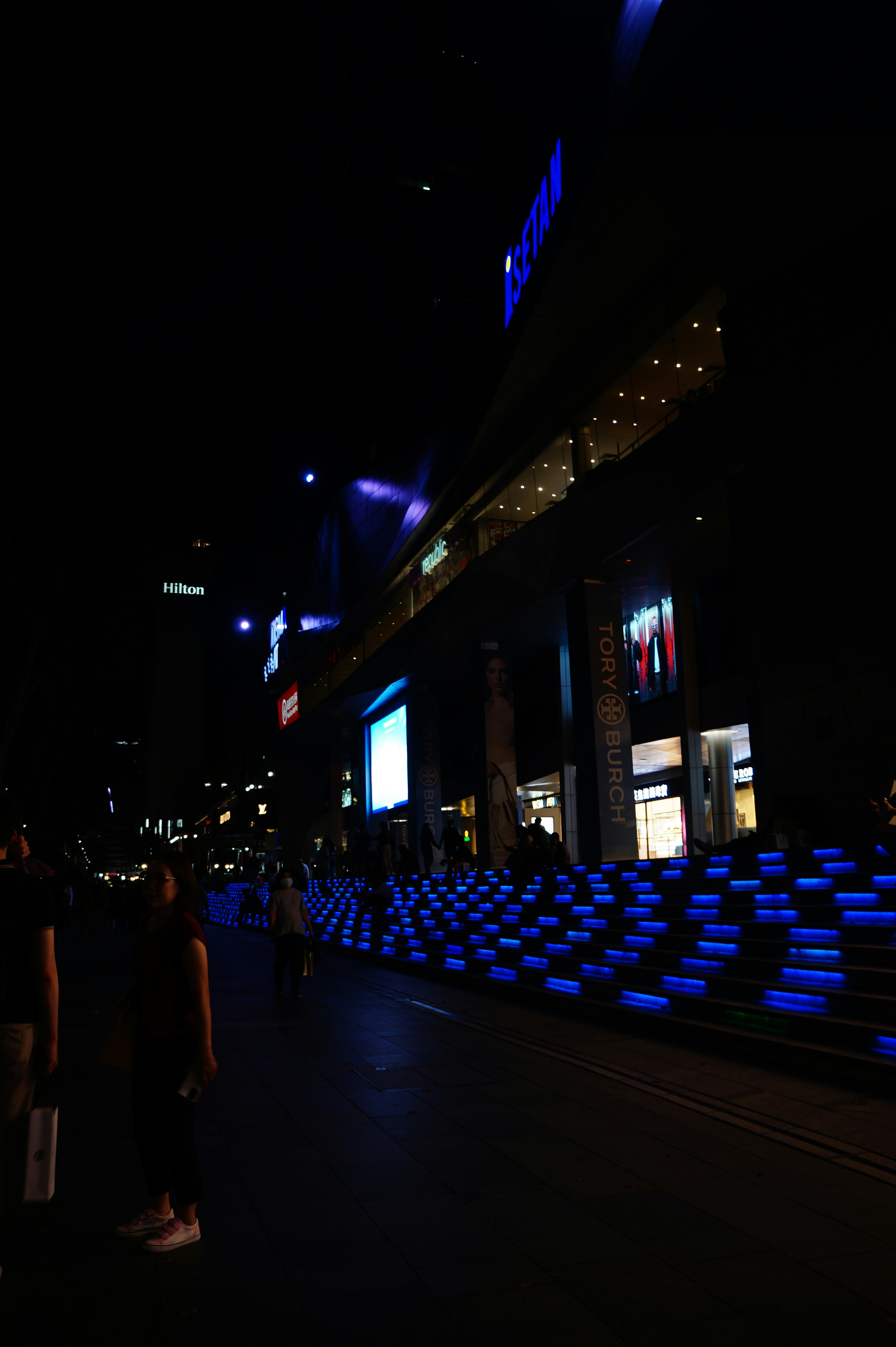 a group of people walking down a street at night
