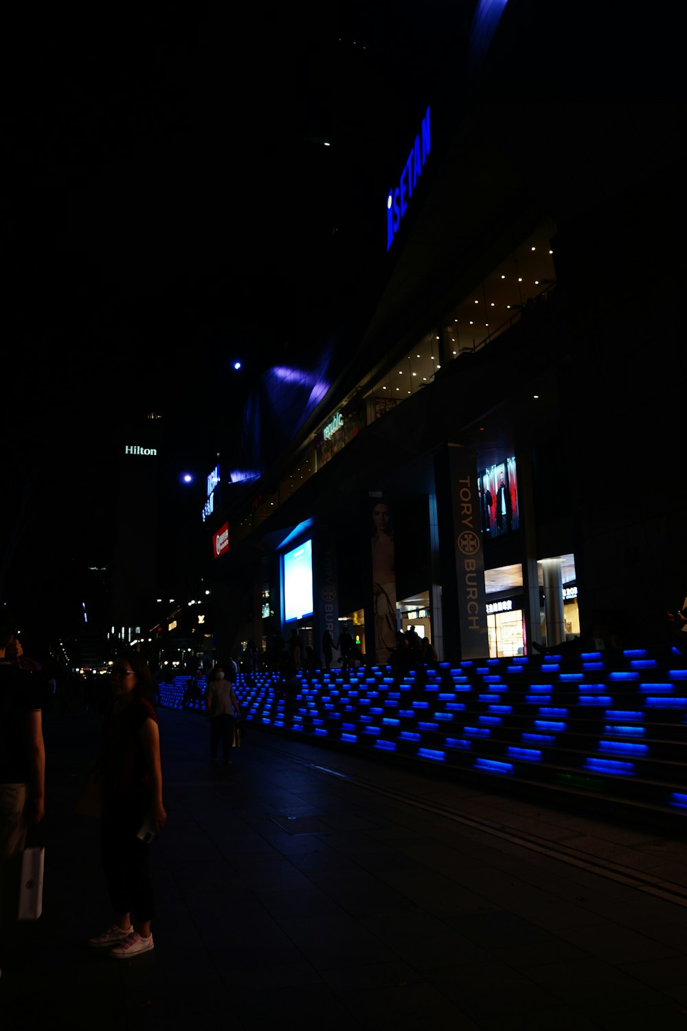 a group of people walking down a street at night