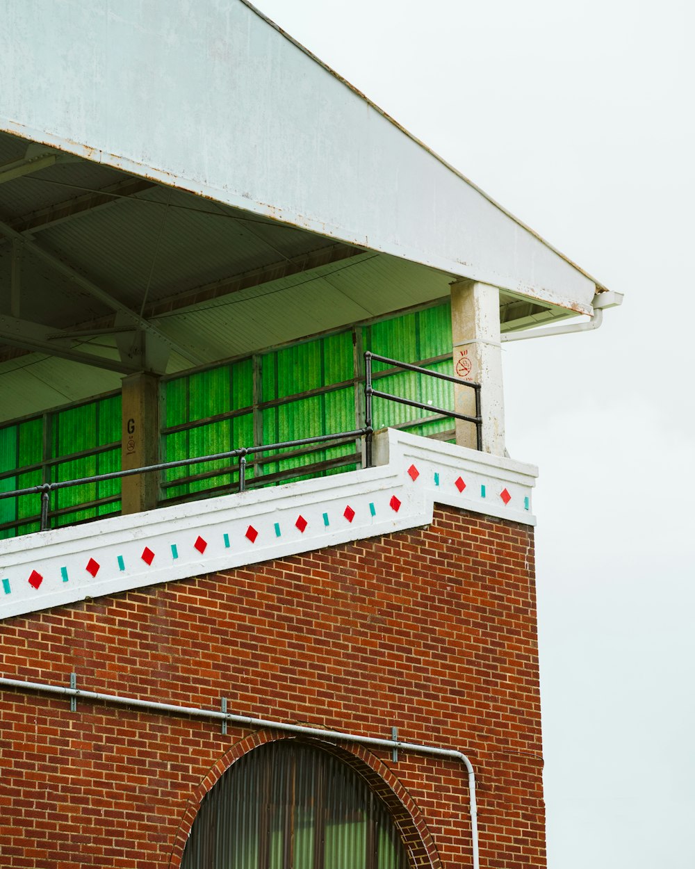 a red brick building with green windows and a white roof