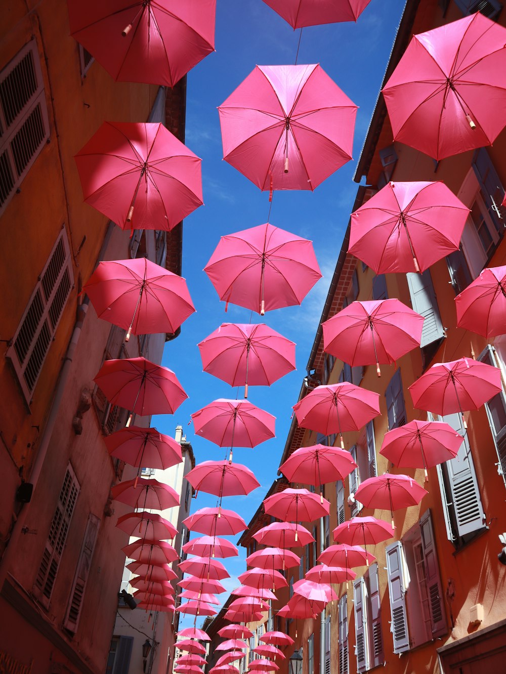 a group of pink umbrellas hanging from a building