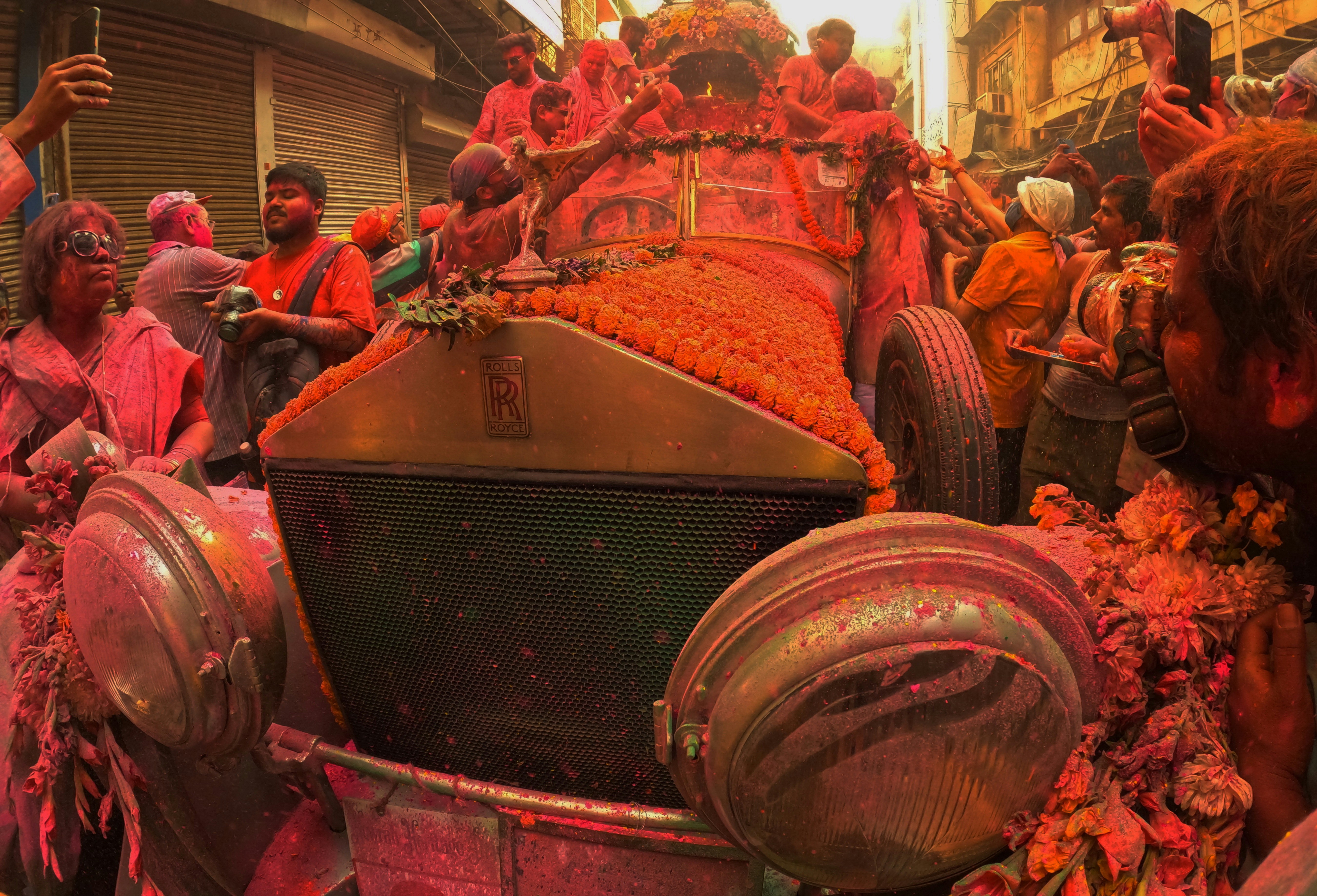 a group of people standing around a car covered in flowers