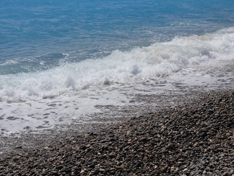 a person standing on a rocky beach next to the ocean