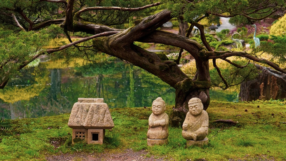 a couple of statues sitting next to a tree