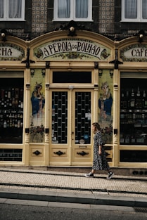 a woman walking down a street past a store front
