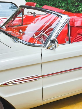 A gleaming vintage convertible parked under soft sunlight, showcasing its polished chrome and elegant curves.