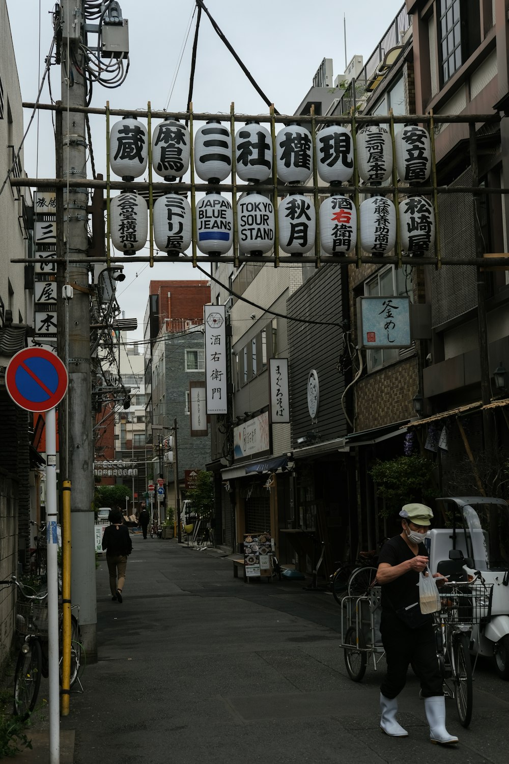 a woman walking down a street next to tall buildings