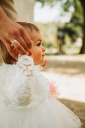 a little girl in a white dress being held by a man