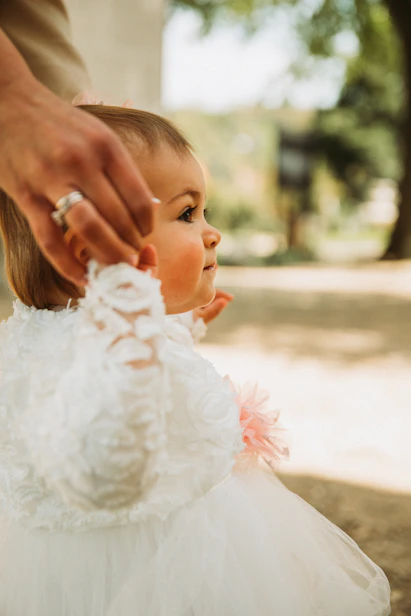 a little girl in a white dress being held by a man