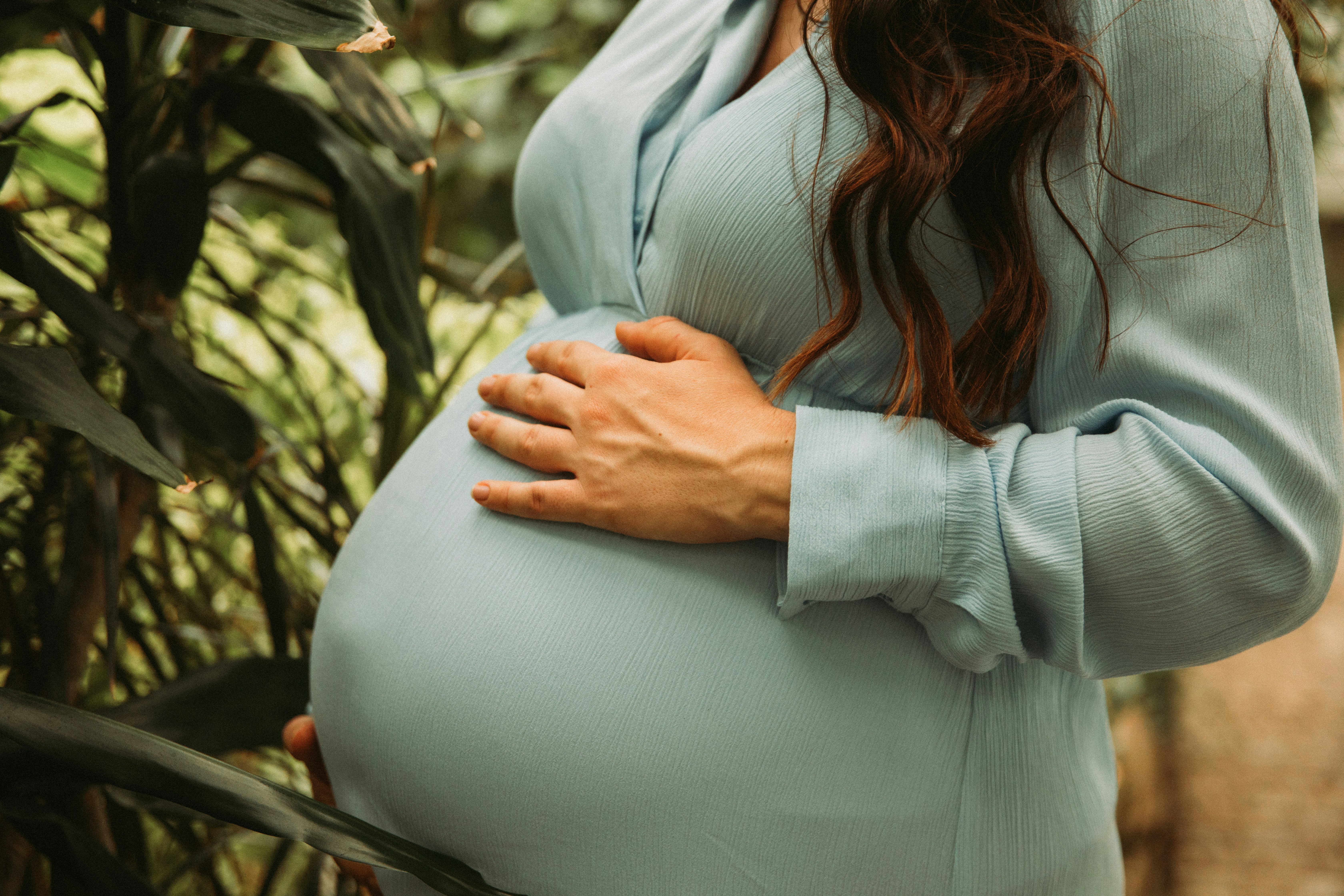 a pregnant woman standing in front of a tree