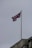 A United Kingdom flag is flying on a flagpole above a building with a cloudy sky in the background. The building appears to have some architectural details visible near the roofline.
