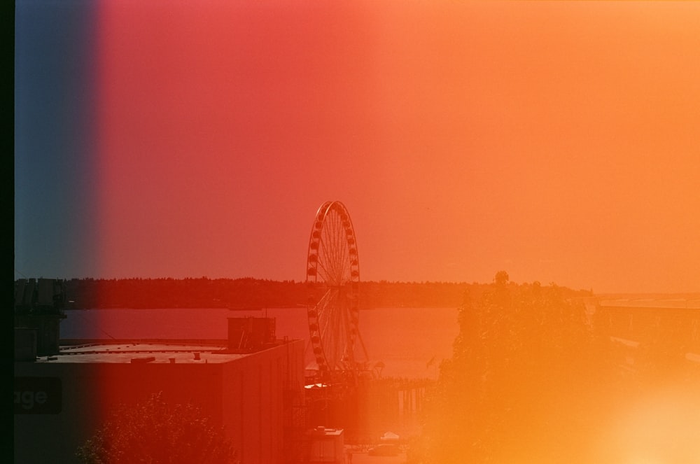 a ferris wheel in the distance with a sunset in the background