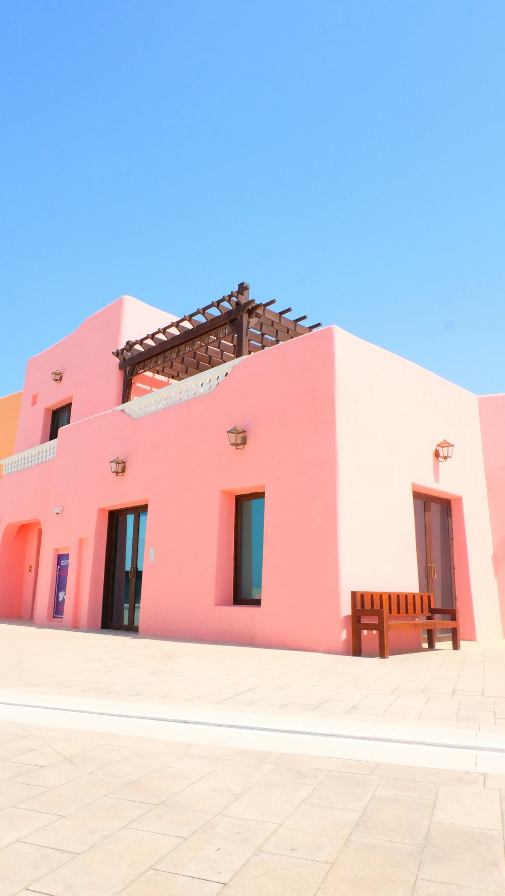 a pink building with a wooden bench in front of it