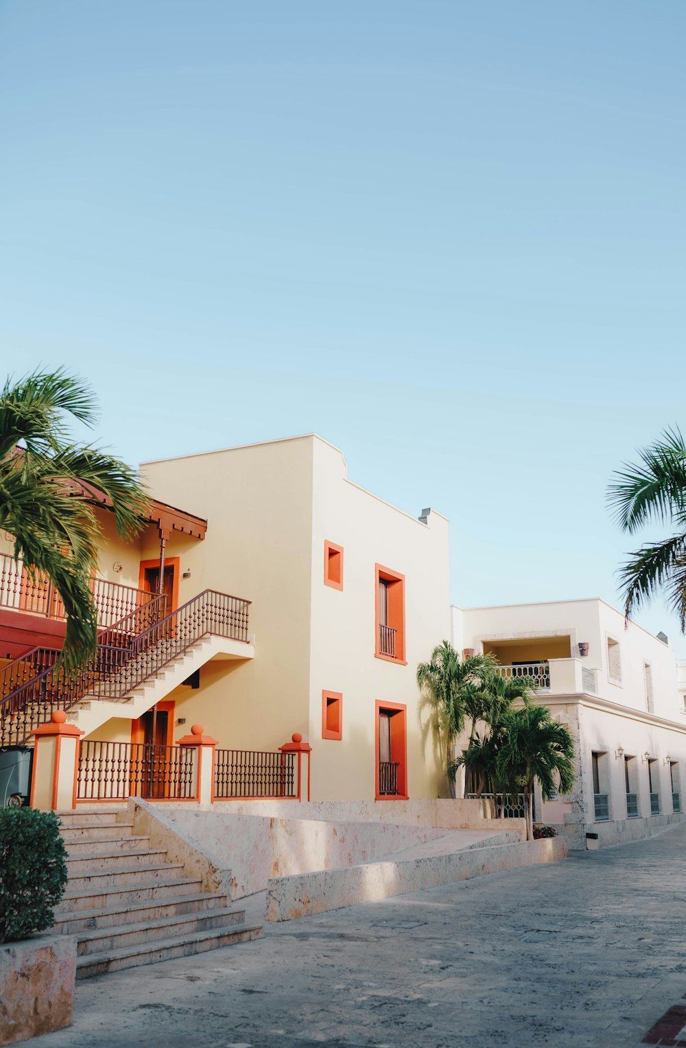 a white building with orange balconies and palm trees