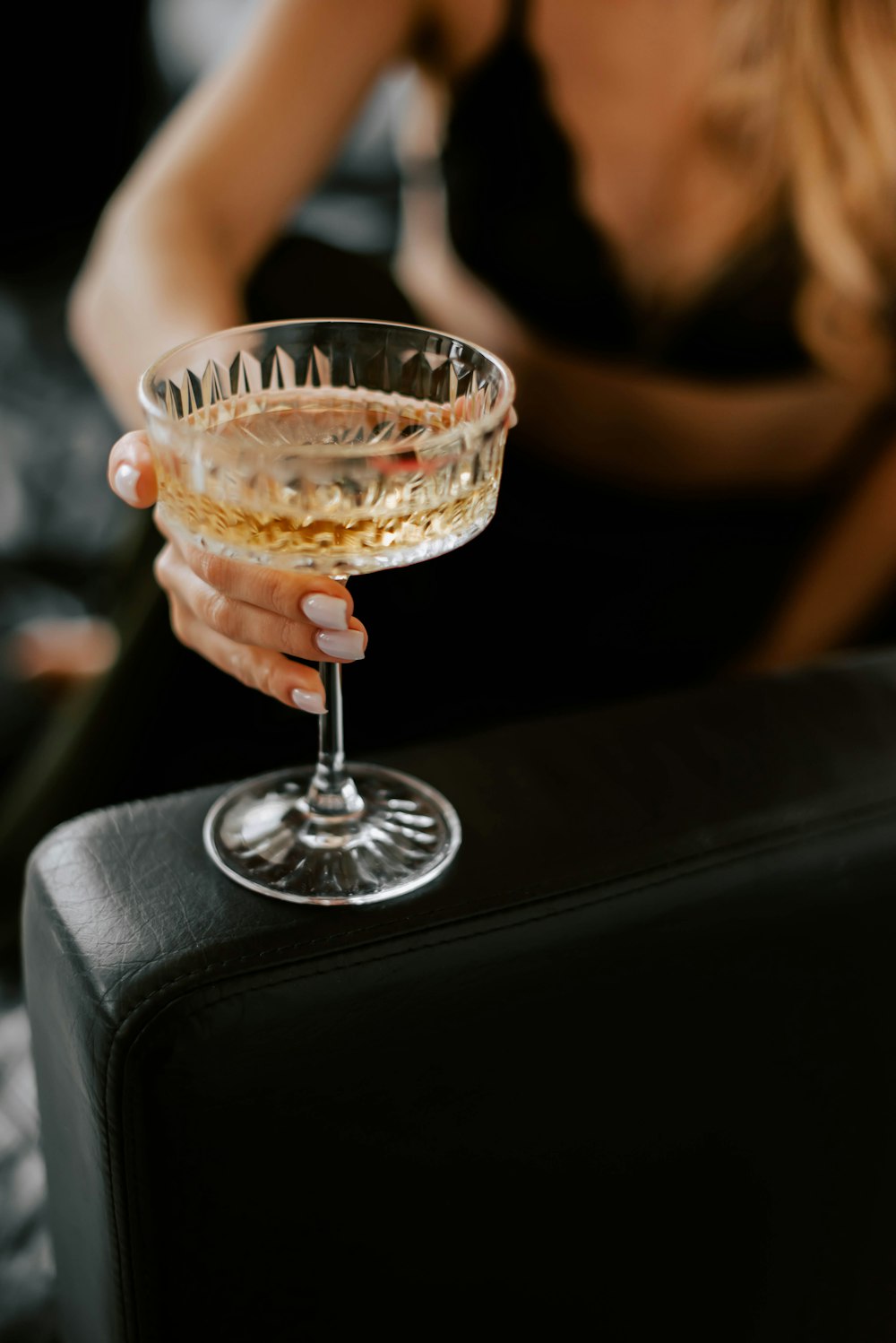 a woman is holding a glass of alcohol