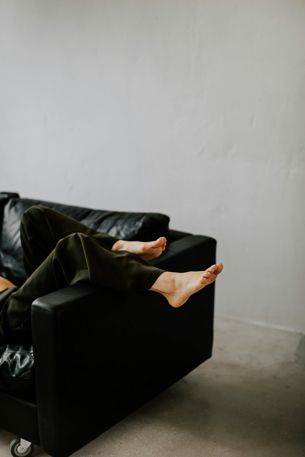 a woman sitting on a black couch with her legs crossed