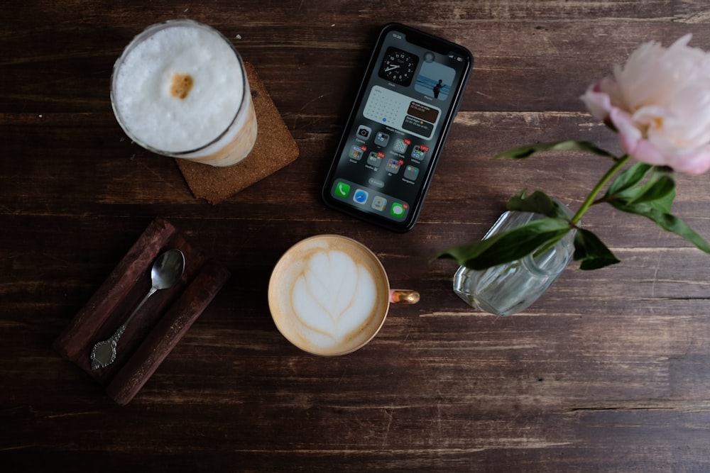 a cup of coffee and a cell phone on a table