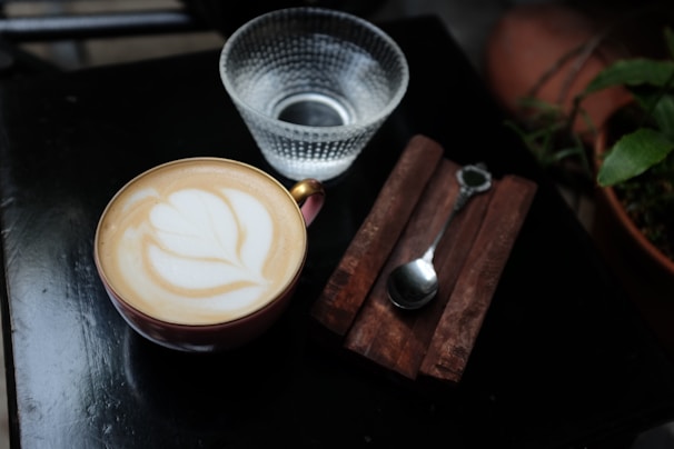 An espresso cup with latte art, sitting next to a fresh wrap filled with colorful vegetables.