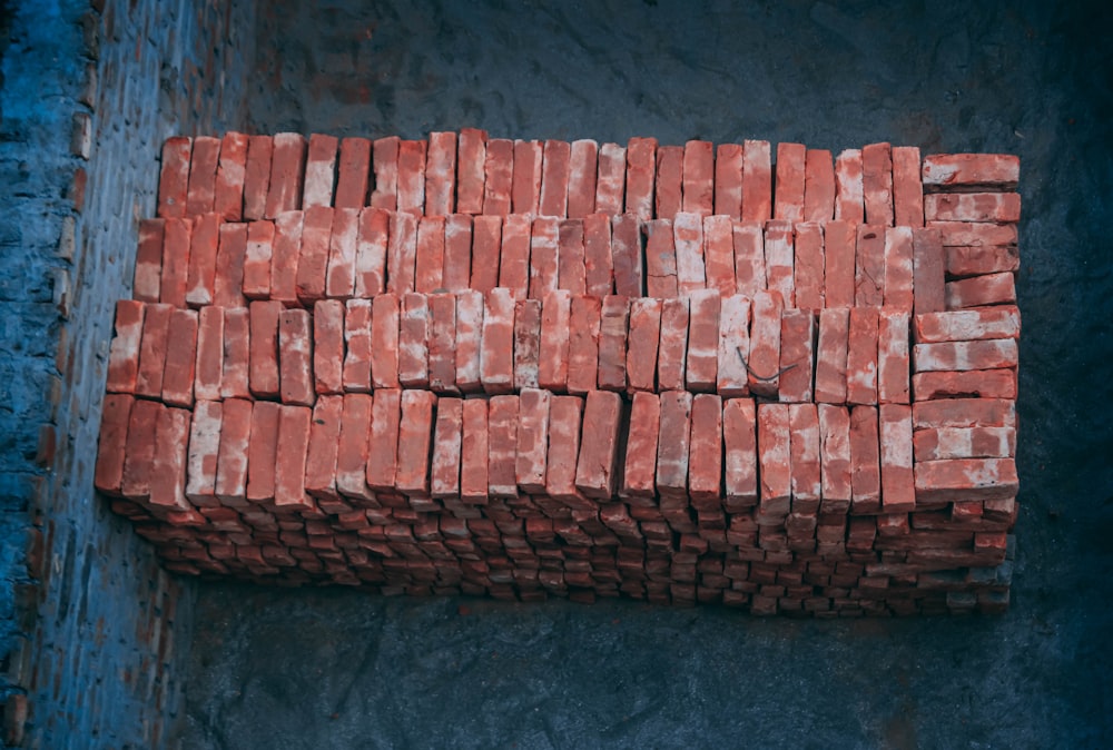 a pile of red bricks sitting on top of a cement slab